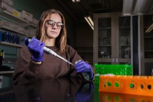 Female student using a pipette in a laboratory.