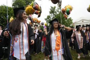 Two students in academic regalia walk the Lawn