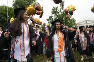 Two students in academic regalia walk the Lawn