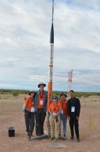 A group of people standing next to a rocket